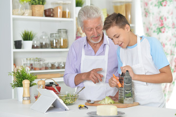 Obraz na płótnie Canvas Portrait of senior man with grandson preparing dinner