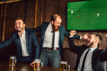Excited young man cheer in pub. They look at each other and wave with hands. Guys watch football game.