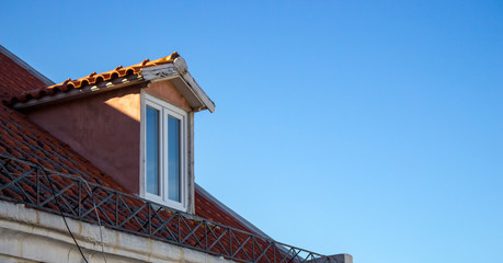 Facade of attic with red roof on blue sky background. Upper storey of ancient building....
