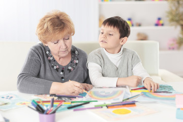 grandmother and grandson paint a rainbow in the nursery