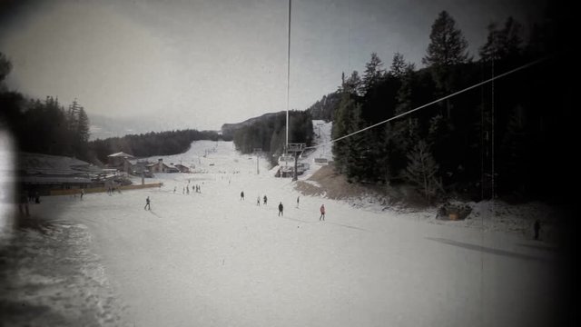 Fake 8mm film projection: spotting people skiing on the snow while on a chairlift or skilift mountain rise.