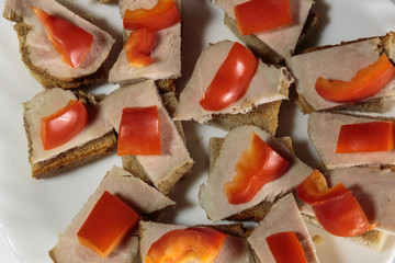 Sandwiches with baked ham and bell pepper on a plate closeup. White background.