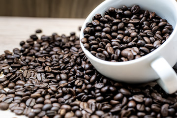 Coffee beans are placed in containers and spread on the background of wood grain.