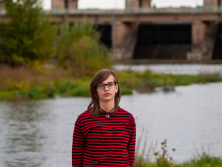 Portrait of a teenage girl gesturing and smiling on the shore of a river