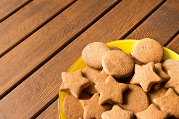 Top view of freshly made cookies in a yellow plate on a wooden table. Empty space for text