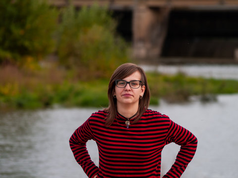 Portrait of a teenage girl gesturing and smiling on the shore of a river