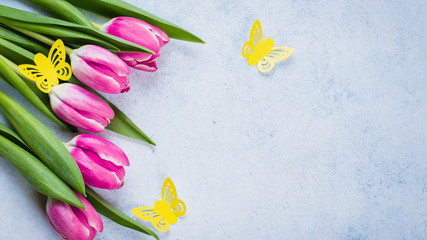 Spring Pink Tulips and Yellow Paper Butterfly on blue stone background for Mother's Day, March 8. Easter Holiday Concept. Top view, flat lay, copy space