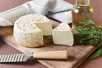 White cheese on a wooden board with olive oil on a brown background