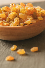 Tasty dried raisins in wooden bowl on tabletop in kitchen