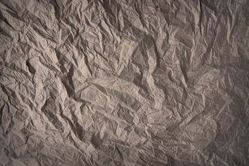Grey-brown crumpled wrapping paper background, texture of grey wrinkled of old vintage paper, creases on the surface of gray paper.