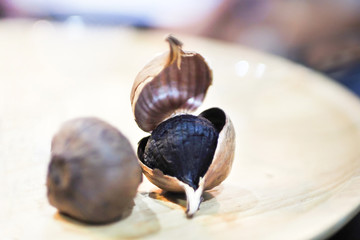 Black Garlic (Allium sativum) with gloves. Fermentation for food preservation.