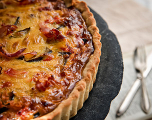 Homemade pie with vegetables, prosciutto and cheese on vintage tray
