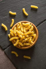 Close up of uncooked pasta in wooden bowl on tabletop in kitchen