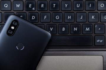 Modern notebook and smartphone copy space. Mobile with dual camera and fingerprint reader