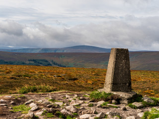 Two Rock Mountain summit on a cloudy summer day in Dublin Mountains, Ireland. Landscape of an Irish mountain peak with a triangulation pillar in the foreground.