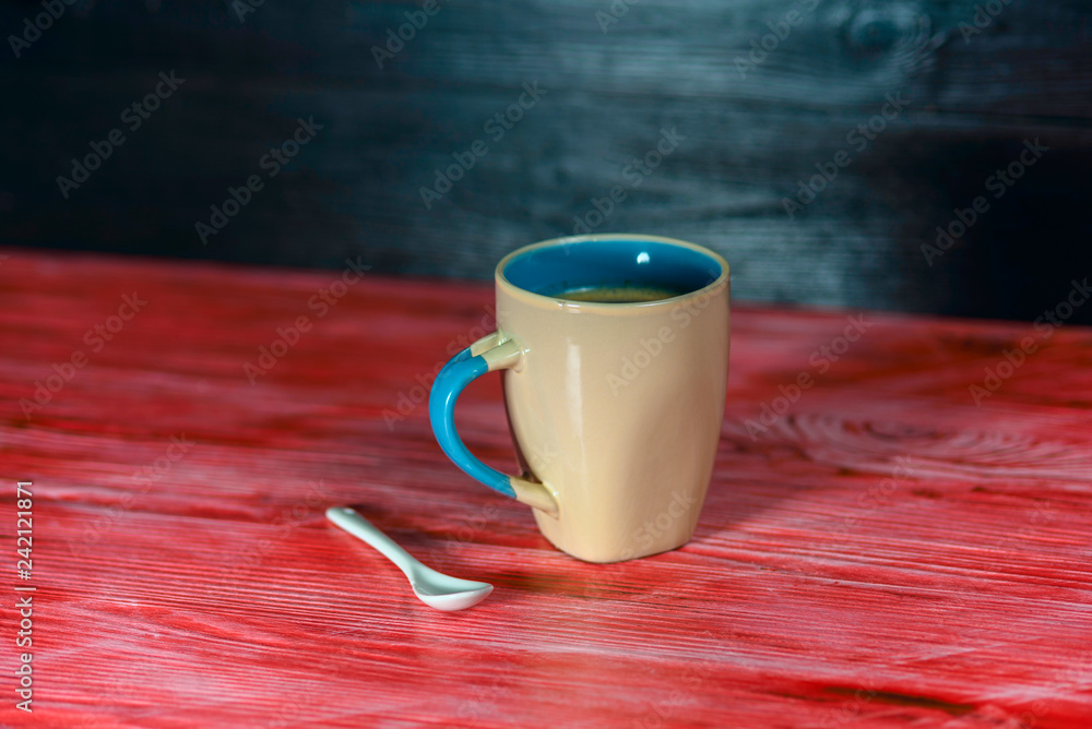 Wall mural a mug of fresh coffee, on a red wooden background.