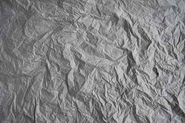 Grey crumpled wrapping paper background, texture of grey wrinkled of old vintage paper, creases on the surface of gray paper.