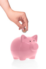 Hand putting coin into piggy bank