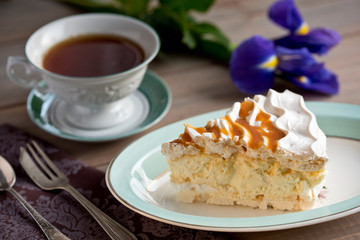 Slice of meringue cake and a cup of tea and iris