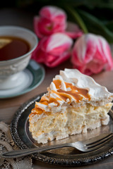 Slice of meringue cake and a cup of tea and tulips