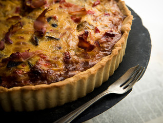 Homemade pie with vegetables, prosciutto and cheese on vintage tray