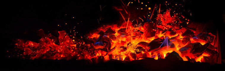 Hot wooden coals in the dark. Grill with hot coals and beautiful magic sparks with blue flame