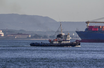Lisbon - Portugal, tugboat assists a cargo ship on the Tagus River