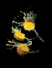 Slice of yellow pineapple with splashing pineapple juice isolated on black background