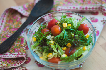 A fresh and healthy salad made with fruits and vegetables on a wooden table.