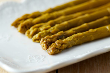 Preserved pickled green asparagus served in white plate