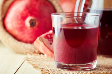 Fresh pomegranate juice in a glass on wooden background