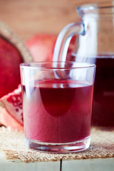 Fresh pomegranate juice in a glass on wooden background