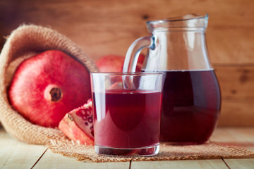 Fresh pomegranate juice in a glass on wooden background
