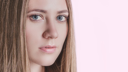 Fototapeta premium cute young girl with blue eyes on light blue background, woman's face close up, youth, freshness, clean skin, skin care concept