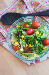 A fresh and healthy salad made with fruits and vegetables on a wooden table.