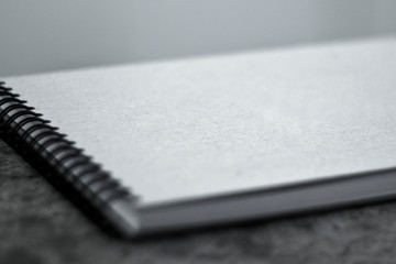 Sketchbook with a hard cardboard cover on the ground. Close-up.