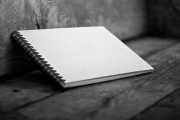 Sketchbook with a hard cardboard cover on a dark wooden background. Close-up.