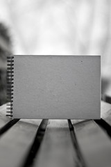 Sketchbook with a hard cardboard cover on a bench. Close-up.
