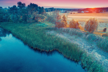 Aerial view of countryside and brook in the evening at sunset light