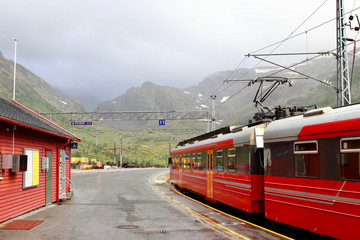 View of Voss mountain train stopped at Myrdal train station with snowy peaks on backgound, Norway.