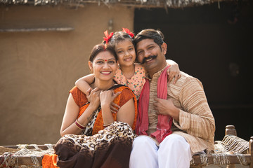 Indian family sitting on traditional bed in village