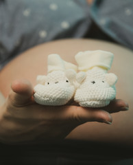 Babyschuhe vor nacktem Babybauch 