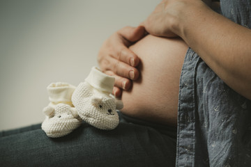 Babyschuhe vor nacktem Babybauch 