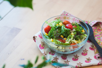 A fresh and healthy salad made with fruits and vegetables on a wooden table.
