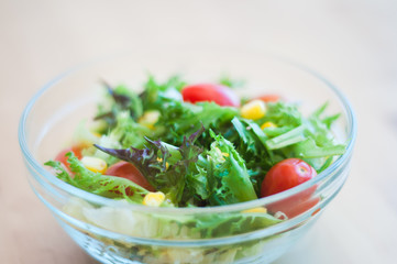 A fresh and healthy salad made with fruits and vegetables on a wooden table.