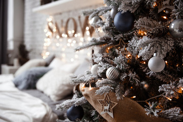 A spacious white light bedroom in a loft style with a decorated Christmas tree and a garland.