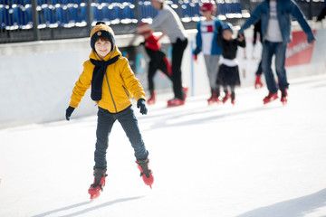 Happy boy with hat and jacket, skating during the day, having fun .