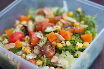 Close up of fresh and healthy salad made with fruits and vegetables in a container.