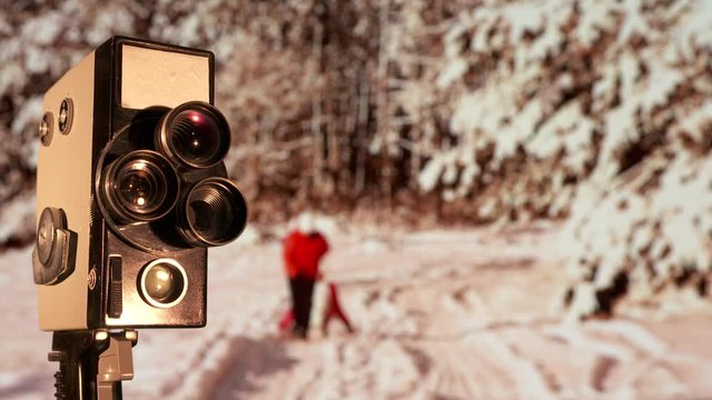 Vintage 8mm film camera in front of flickering old movie background. Retro stylized film of Christmas holiday family home movie.