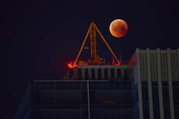 Construction crane on the background of a full red moon. Red moon, total lunar eclipse.